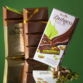 Stacked chocolate bars include one in gold wrapping and another in white packaging labeled "Dubaco," with pistachios hinting at a luscious pistachio cream filling inside the Beyoglu - Dubaco Premium Dubai Chocolate Bar - 200g.